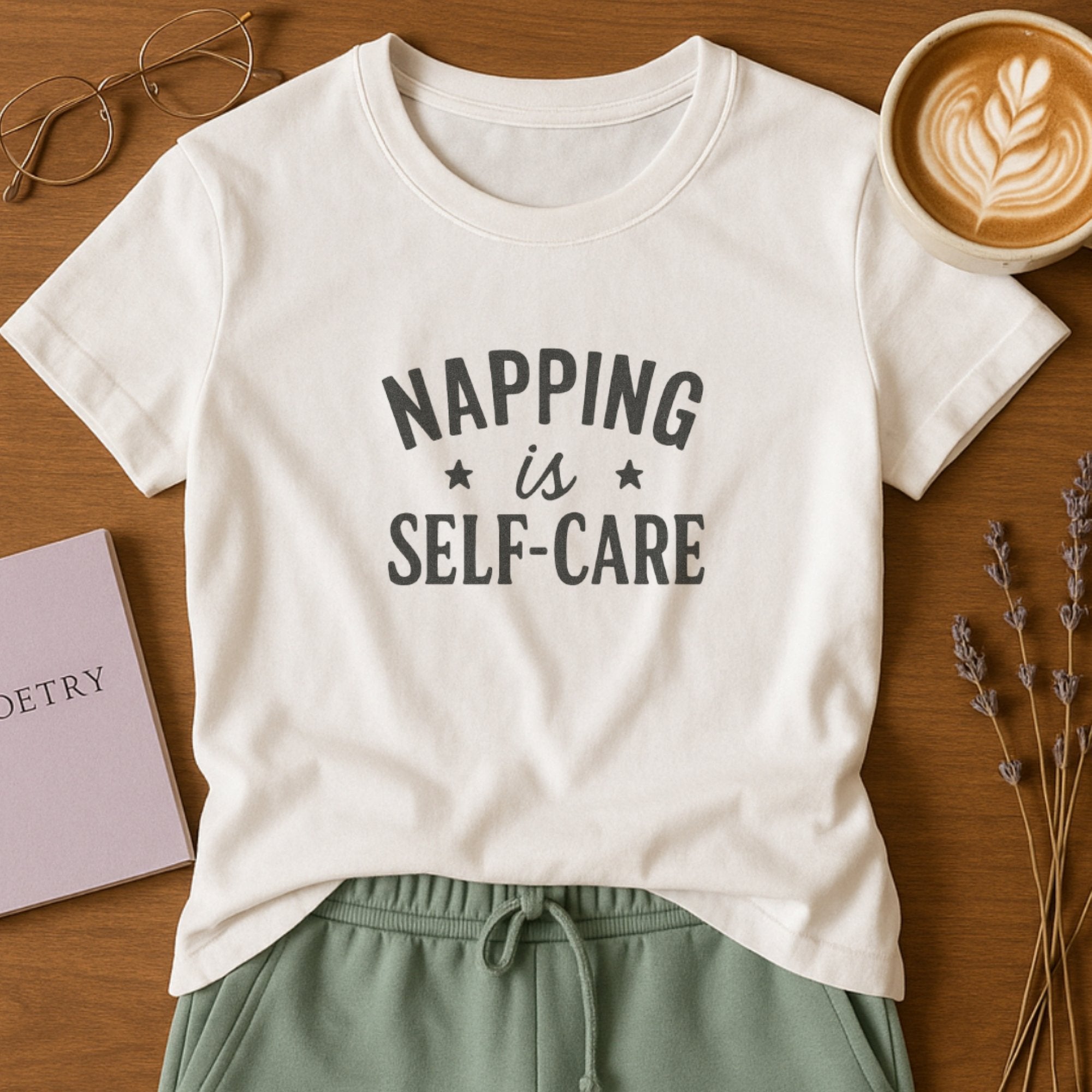White self-care t-shirt with bold typography saying “Napping Is Self-Care,” a cozy and relatable mental health wellness design
