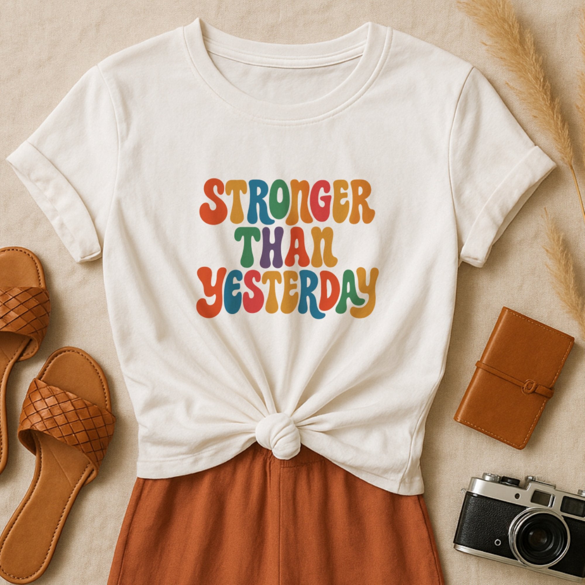 White t-shirt with colorful retro bubble lettering that says “Stronger Than Yesterday,” celebrating growth, resilience, and mental strength