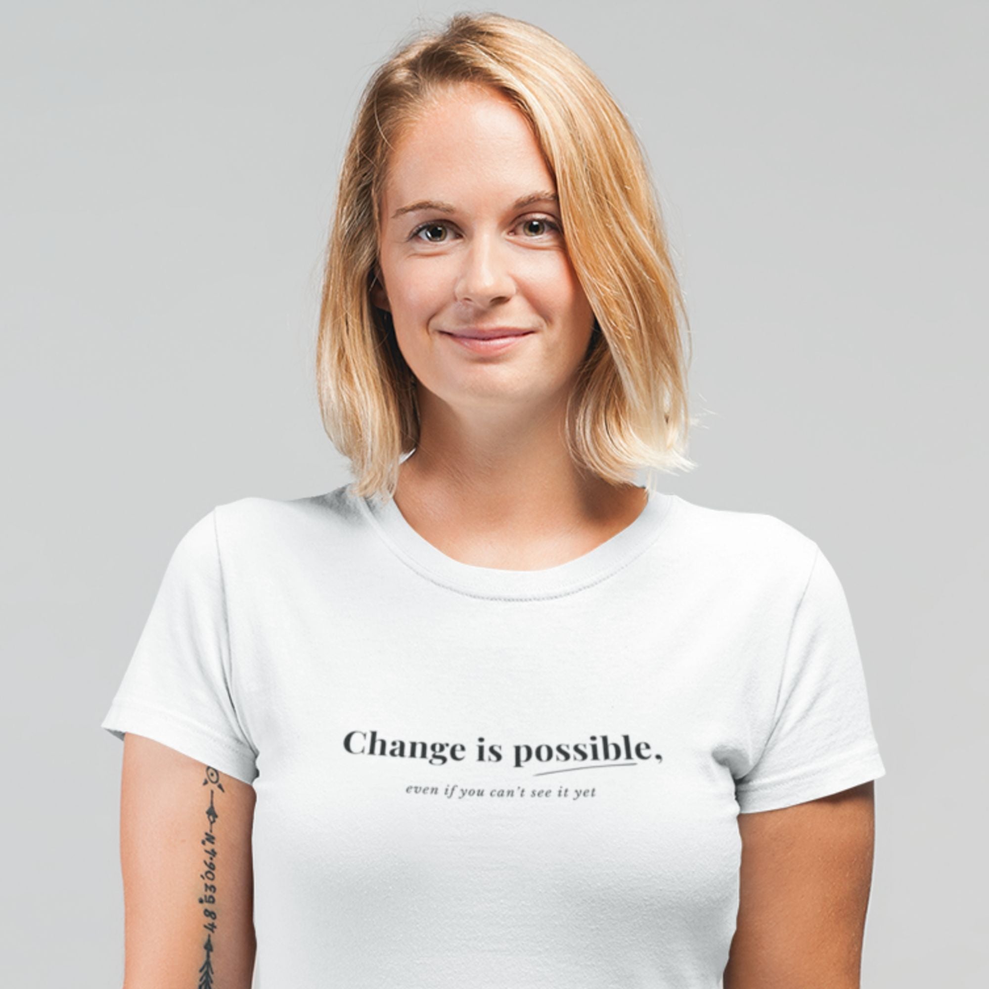 Woman wearing a white t-shirt with 'Change is possible. even if you can't see it yet.' text on a gray background