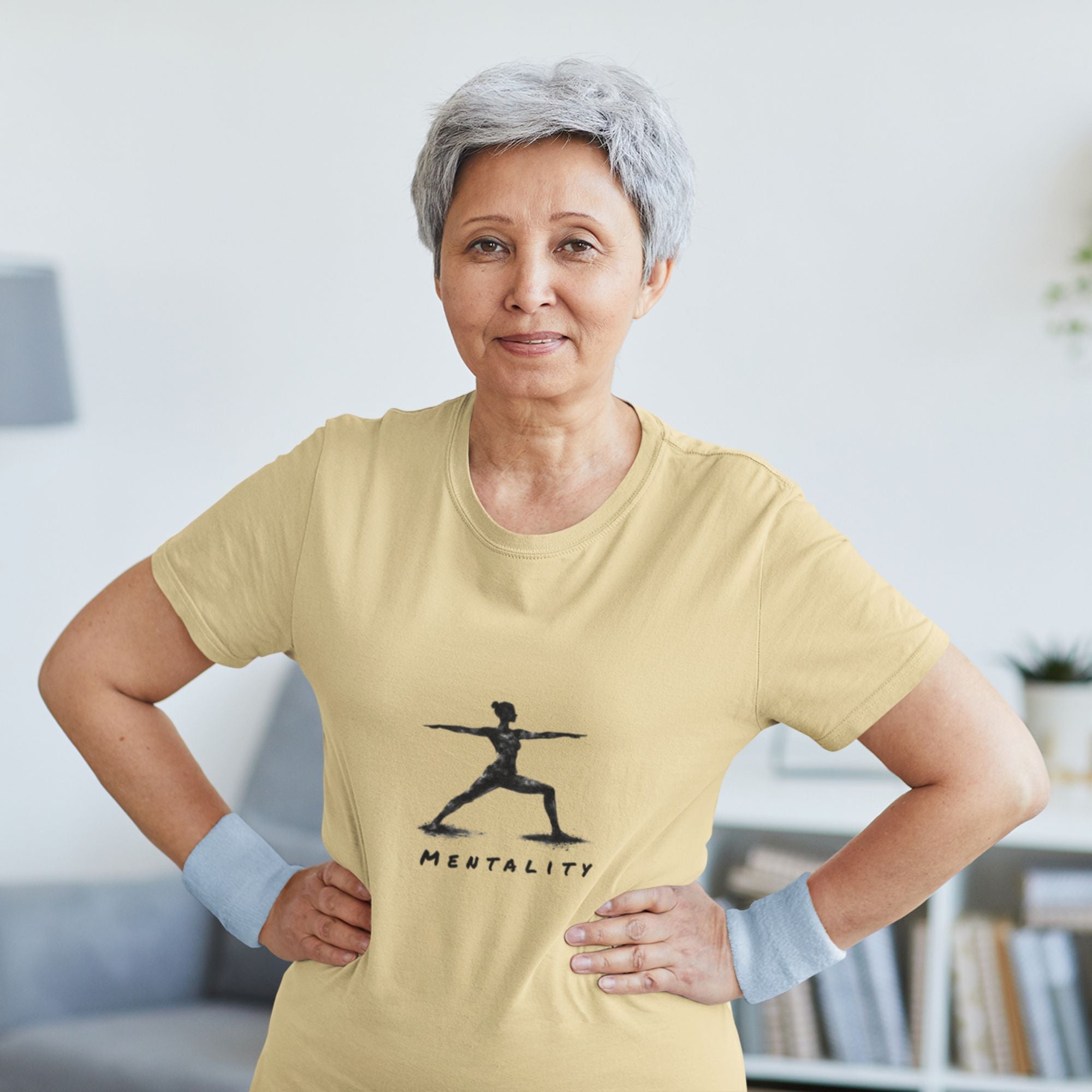 Woman wearing a yellow t-shirt with a graphic design and text indoors.