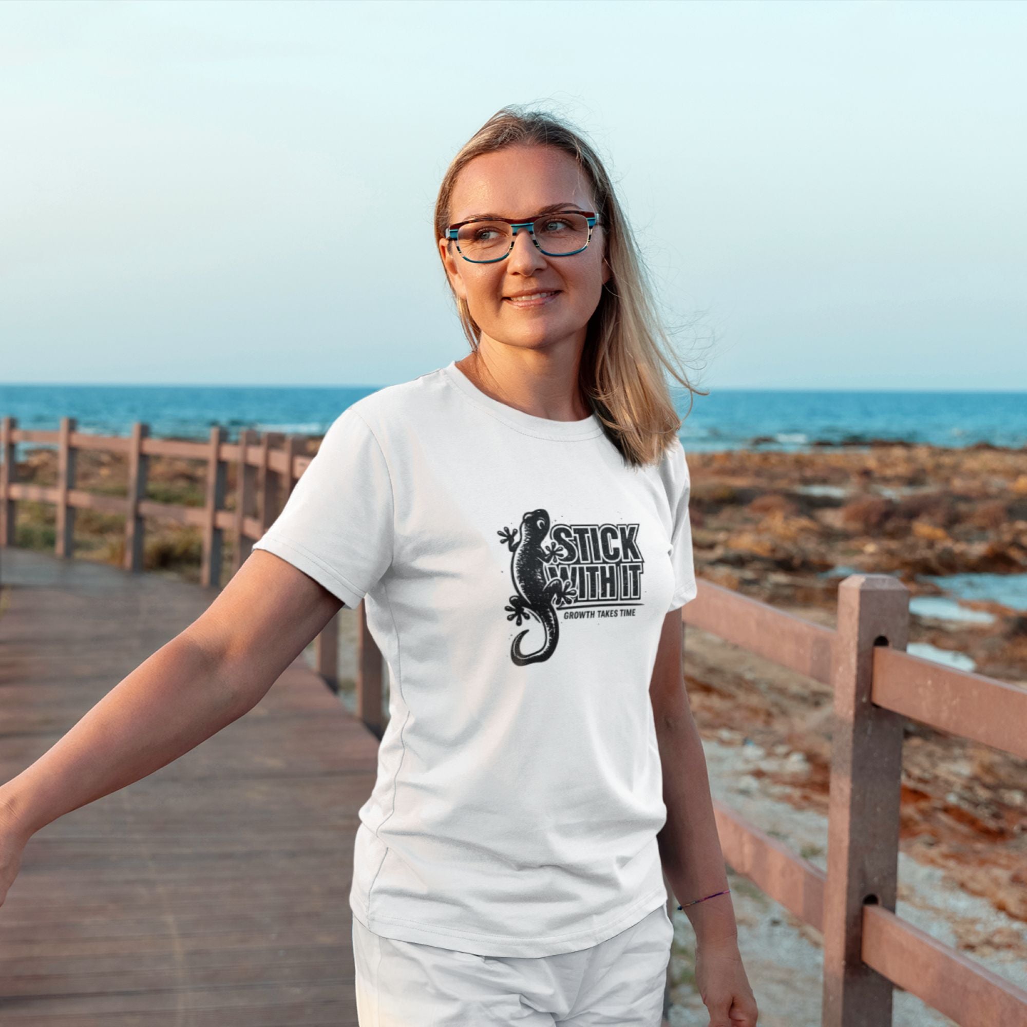Person wearing a white t-shirt with a graphic design by the ocean