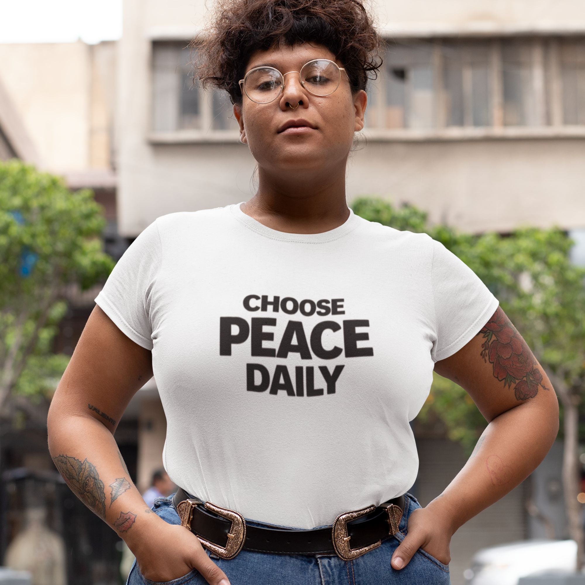 Person wearing a white t-shirt with 'CHOOSE PEACE DAILY' text in an urban setting