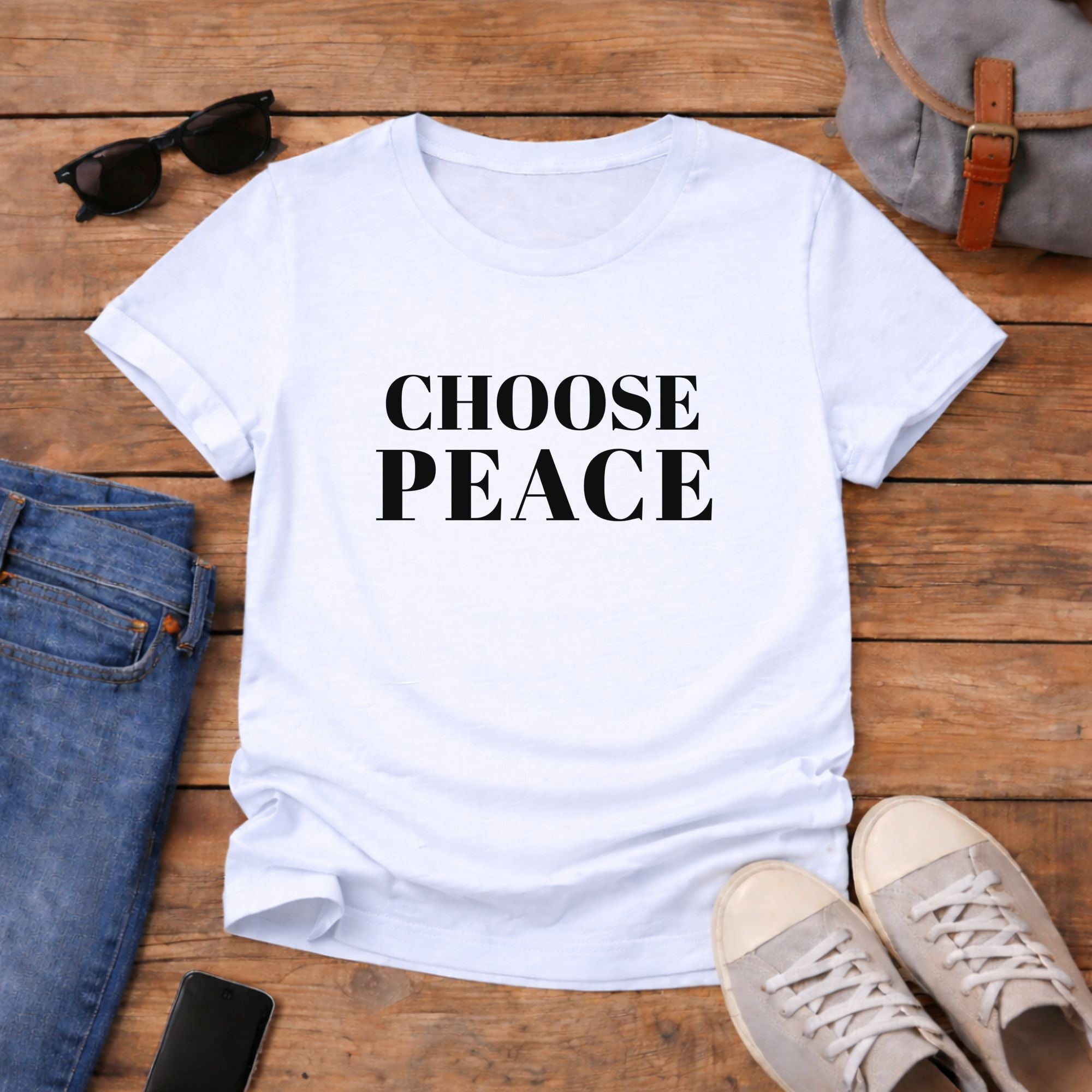 White t-shirt with 'CHOOSE PEACE' text on a wooden surface with jeans, sneakers, and sunglasses.