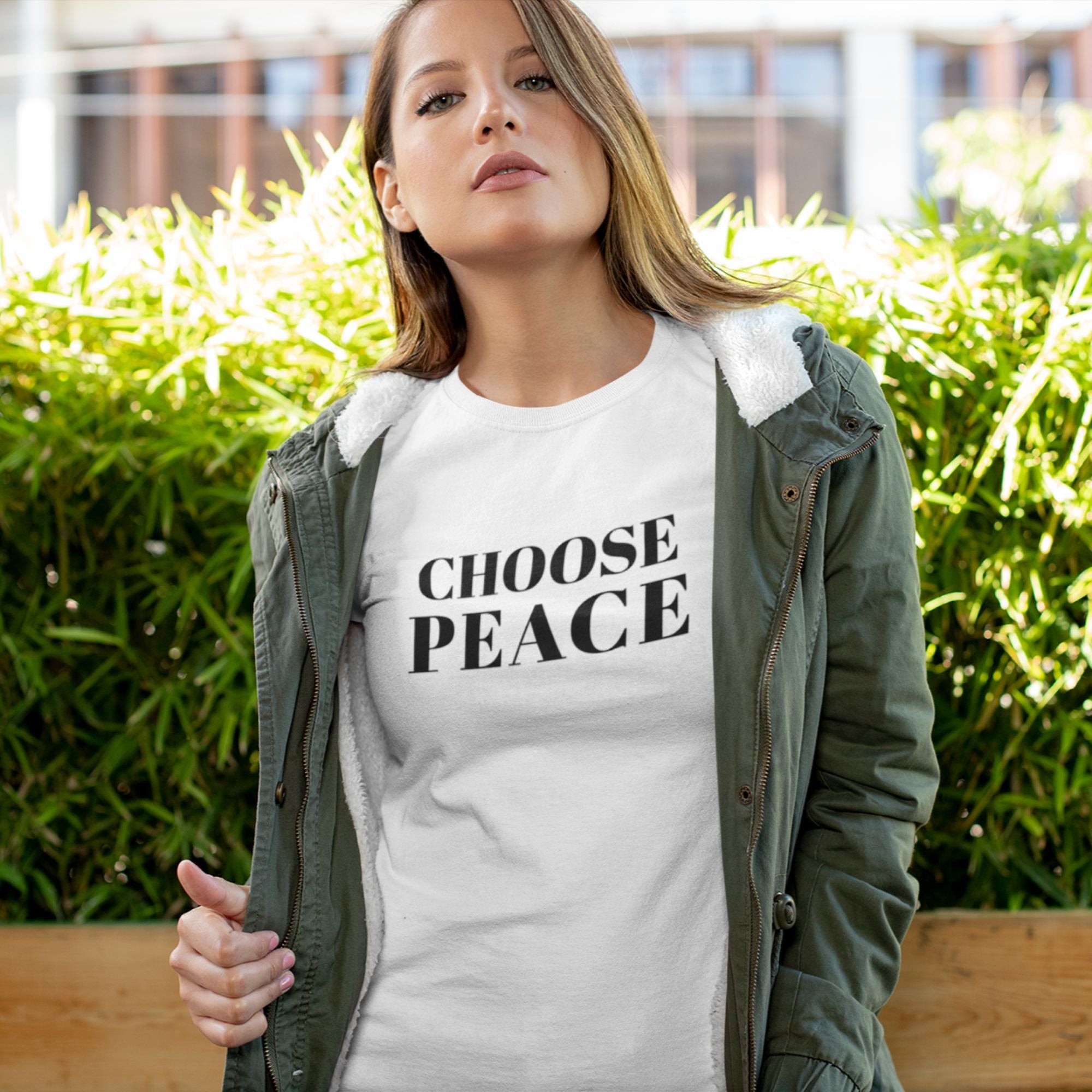 Woman wearing a 'Choose Peace' t-shirt outdoors with greenery in the background